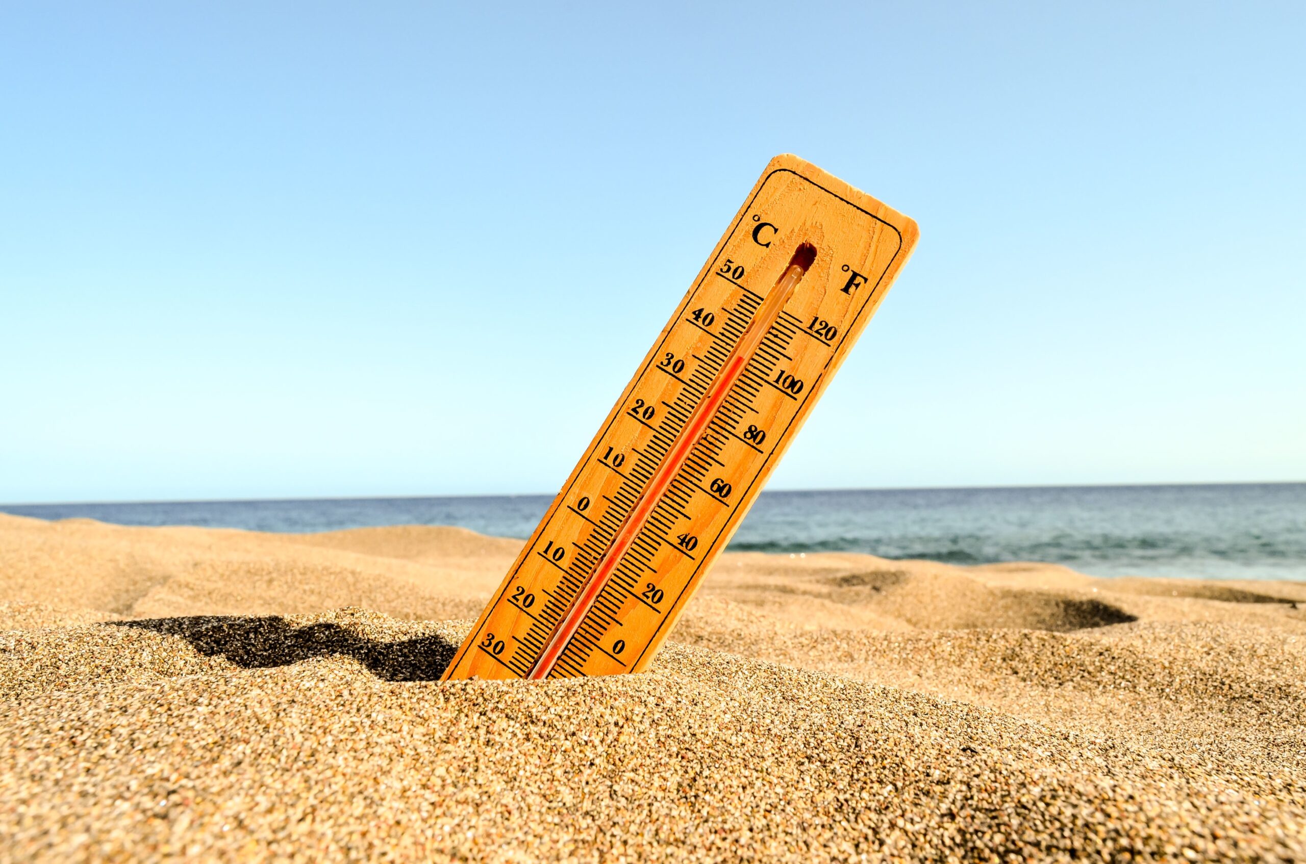 Selective focus shot of a thermometer in the beach sand with a blurred background calor
